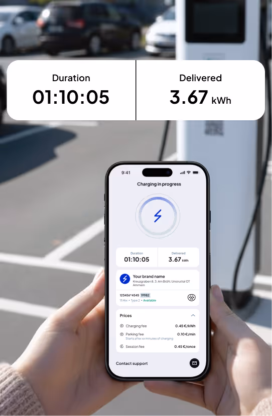 Person holding smartphone showing electric vehicle charging app with duration 01:10:05 and delivered energy 3.67 kWh on screen, next to an EV charging station.